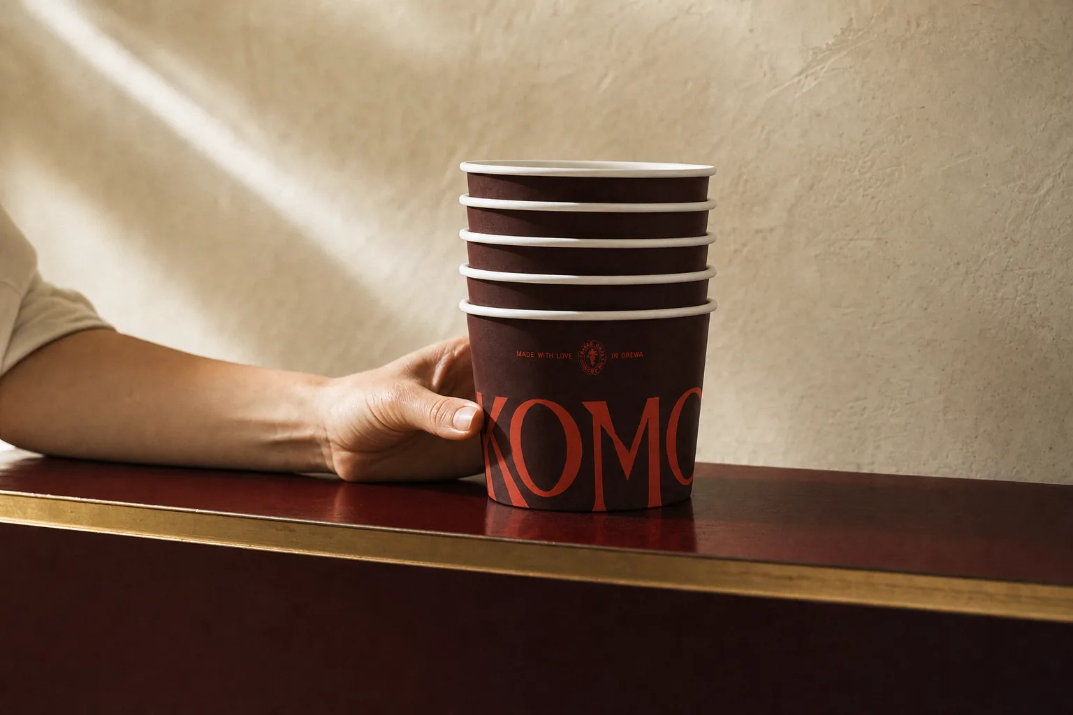 Detail of the counter edge in brushed brass with a stack of Komo cups